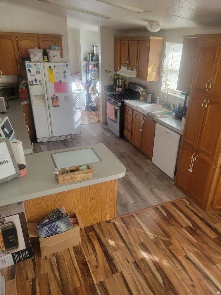 Kitchen featuring wood finish cabinets, dark wood finished floors, and white appliances