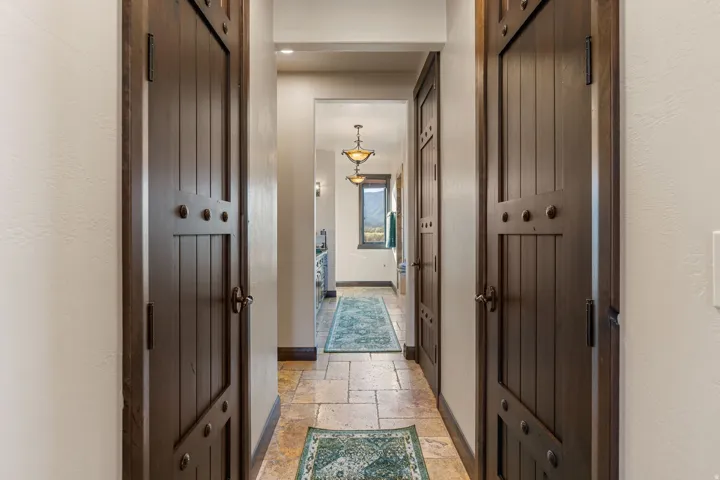 Hallway featuring stone tile floors and baseboards