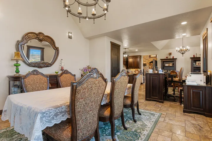 Dining room with suspended lighting, stone tile flooring, and vaulted ceiling