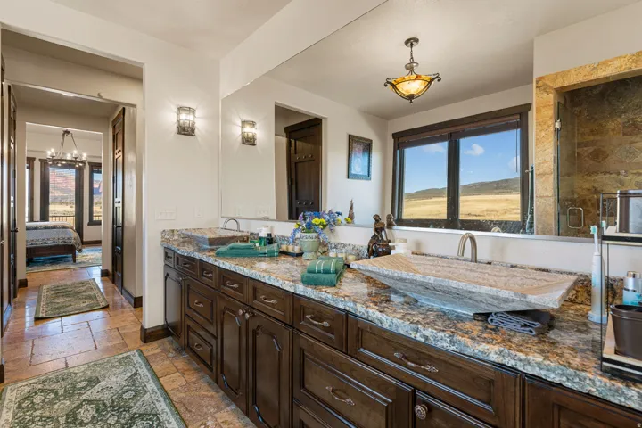 Bathroom featuring stone tile flooring, double vanity, plenty of natural light, and connected bathroom