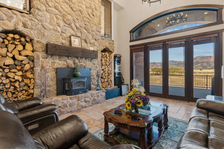 Living room featuring a mountain view, stone tile flooring, a high ceiling, and a wood stove