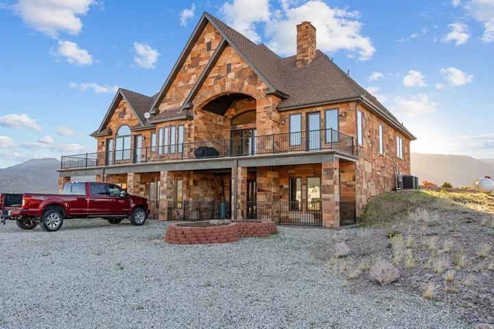 View of front of property featuring stone siding, a mountain view, a chimney, and a balcony