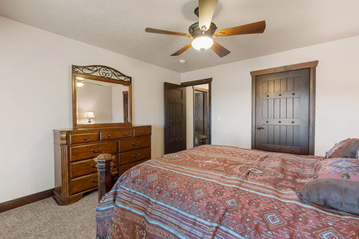 Bedroom featuring light colored carpet, a ceiling fan, a closet, and a textured ceiling