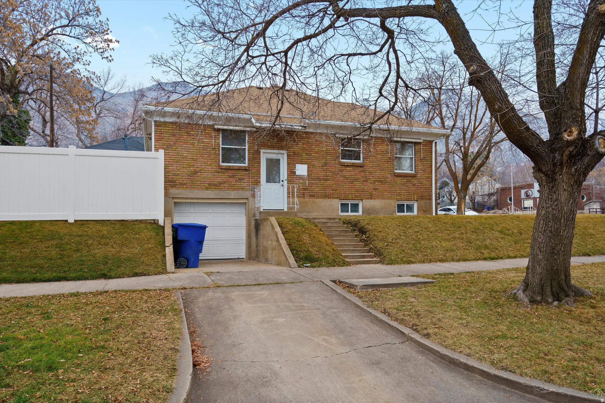 View of front of property featuring brick siding, a front yard, concrete driveway, and a garage