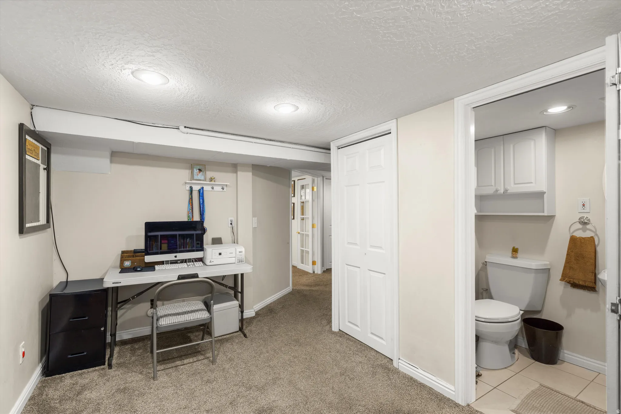 Office area featuring a textured ceiling and light colored carpet