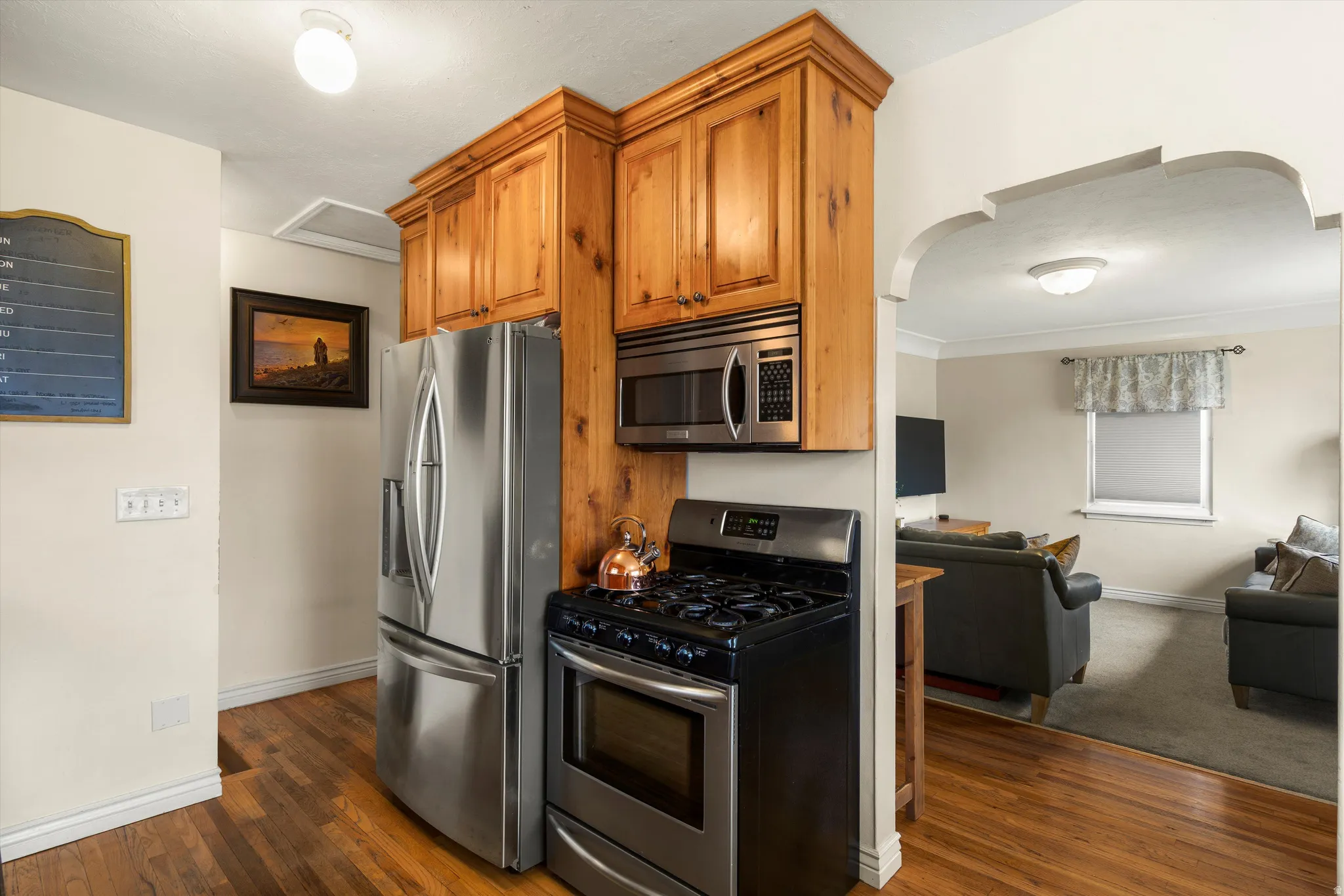 Kitchen featuring stainless steel appliances, wood finish cabinets, arched walkways, and dark wood-style floors