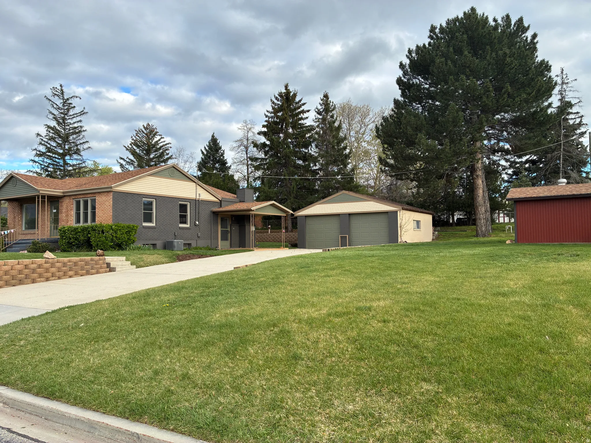 View of front of house featuring a front lawn, a 2 car detached garage, an storage shed with electricity run. The lot is not only large, but mostly leveled out and usable. You could easiley put a basketball hoop on the garage.