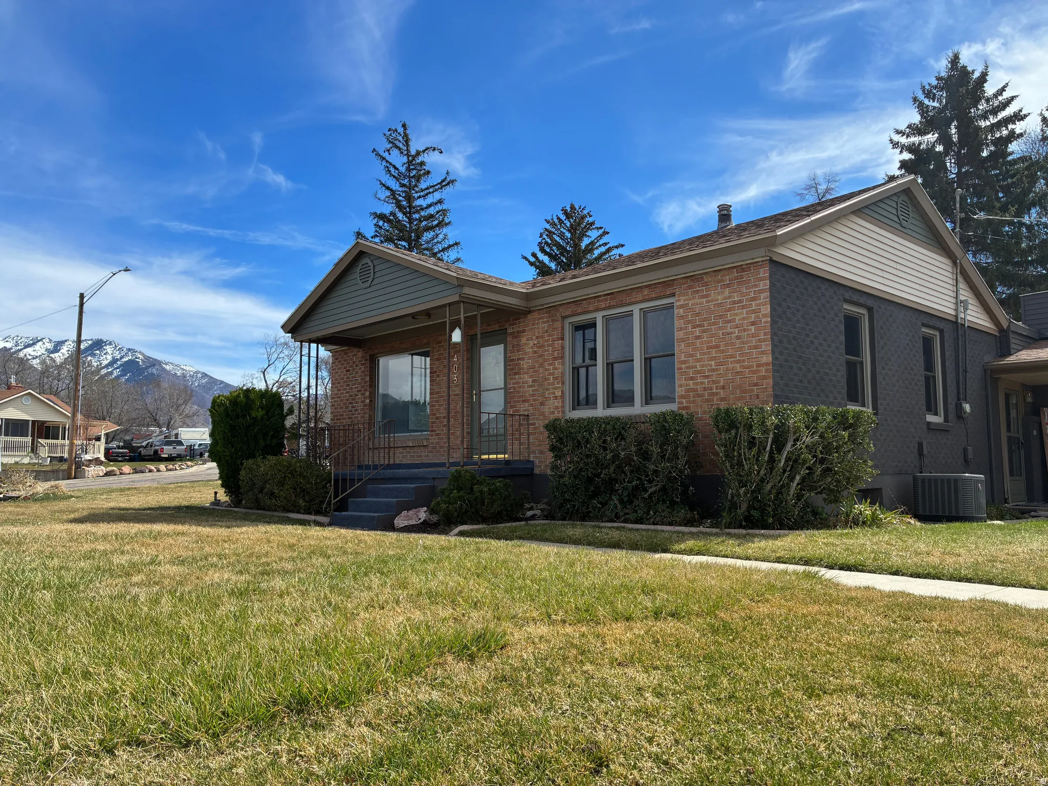 View of front of home featuring a mountain view, brick siding, a front yard, and a porch