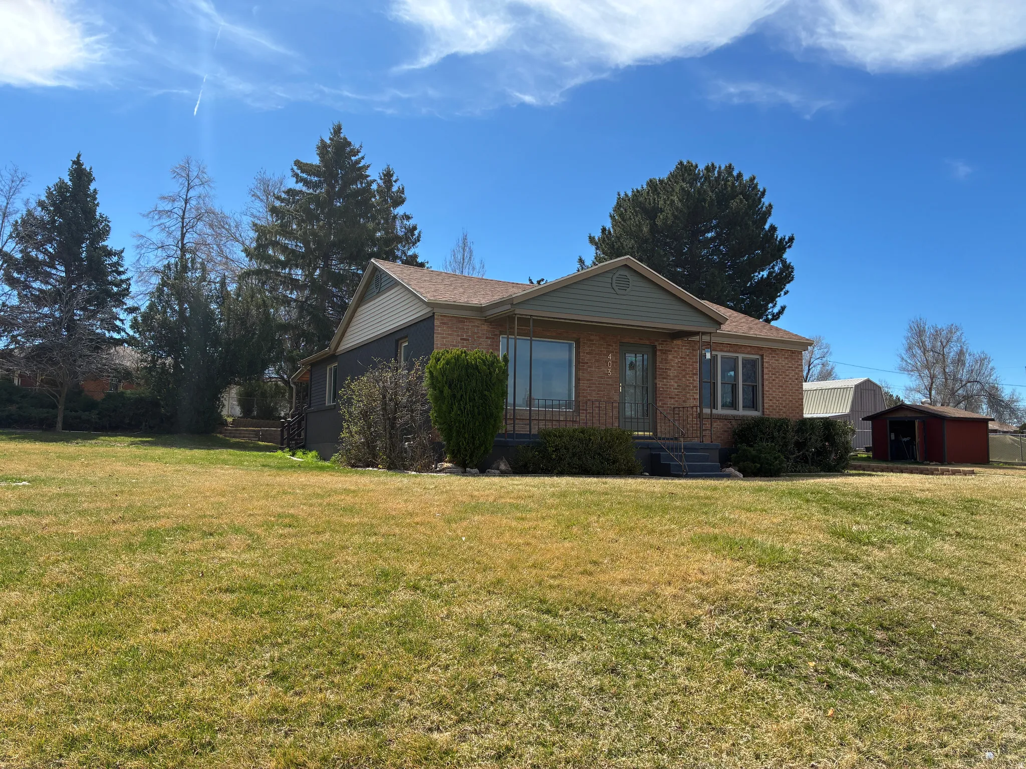 Ranch-style house with brick siding, a front lawn, and a storage shed