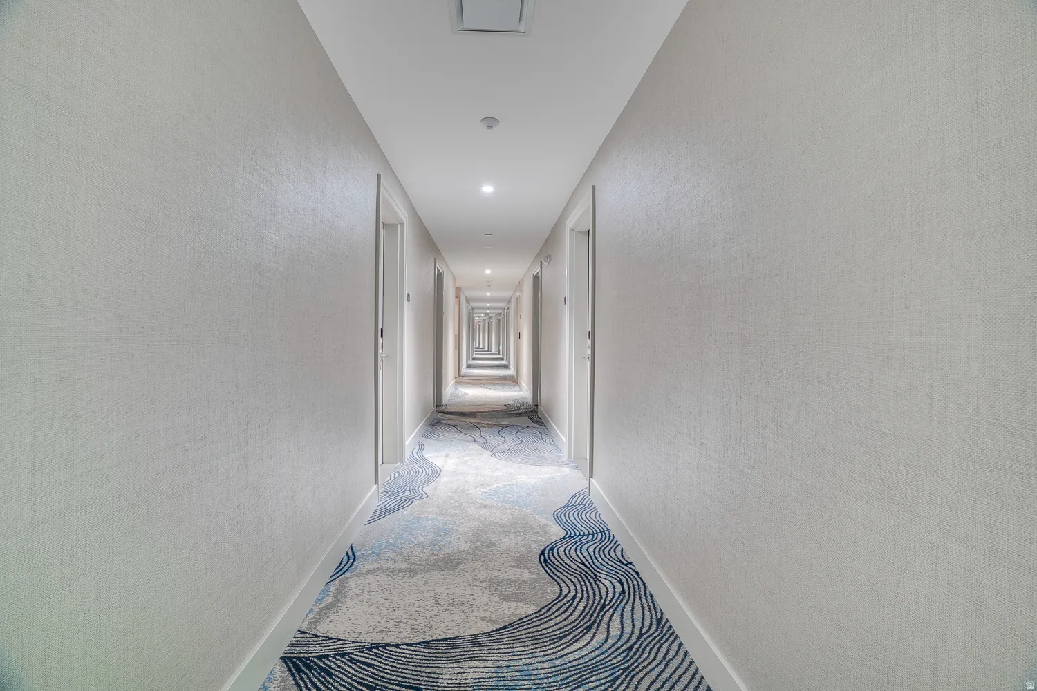 Hallway with carpet floors, recessed lighting, and a textured wall