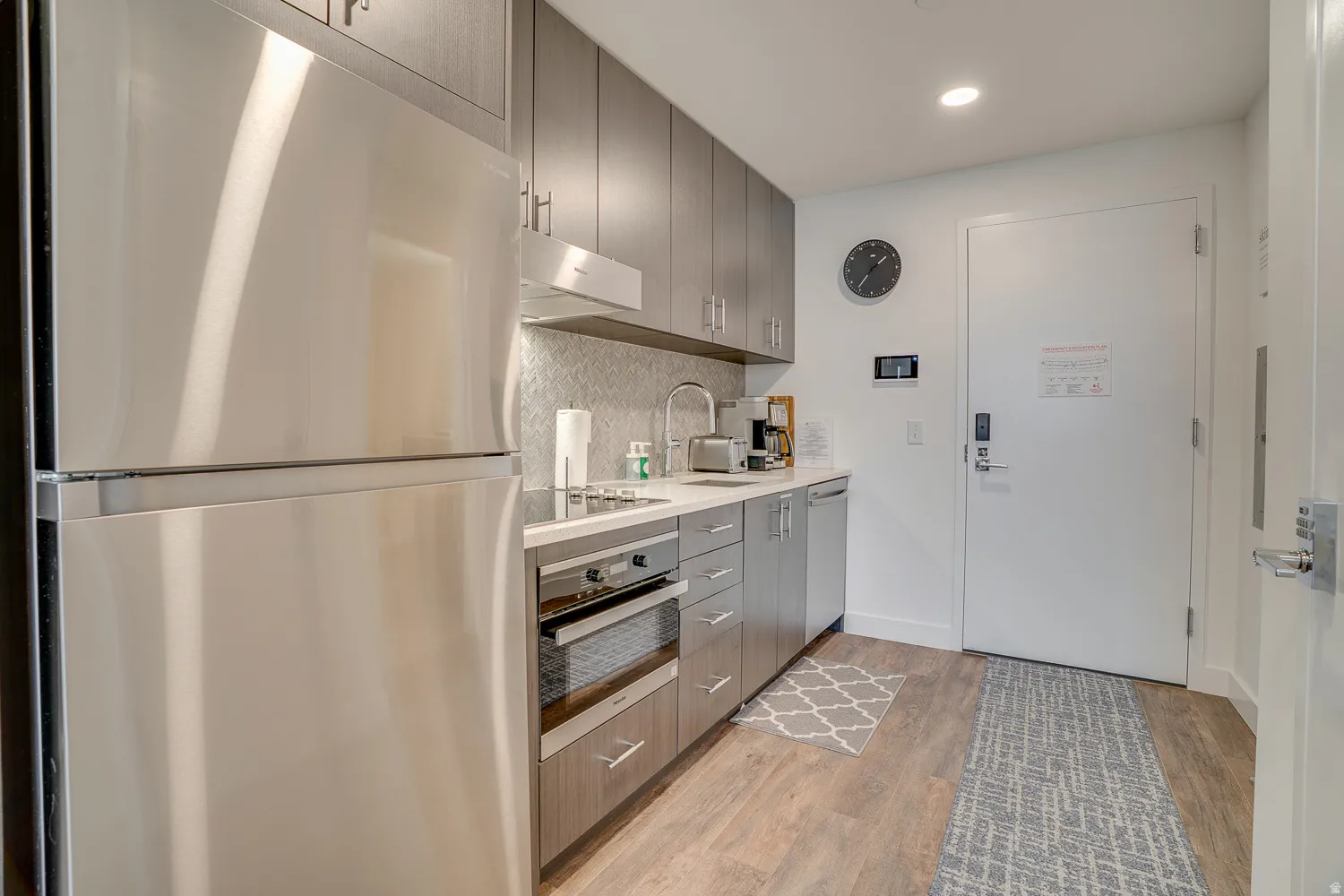 Kitchen featuring stainless steel appliances, light countertops, backsplash, light wood finished floors, and recessed lighting