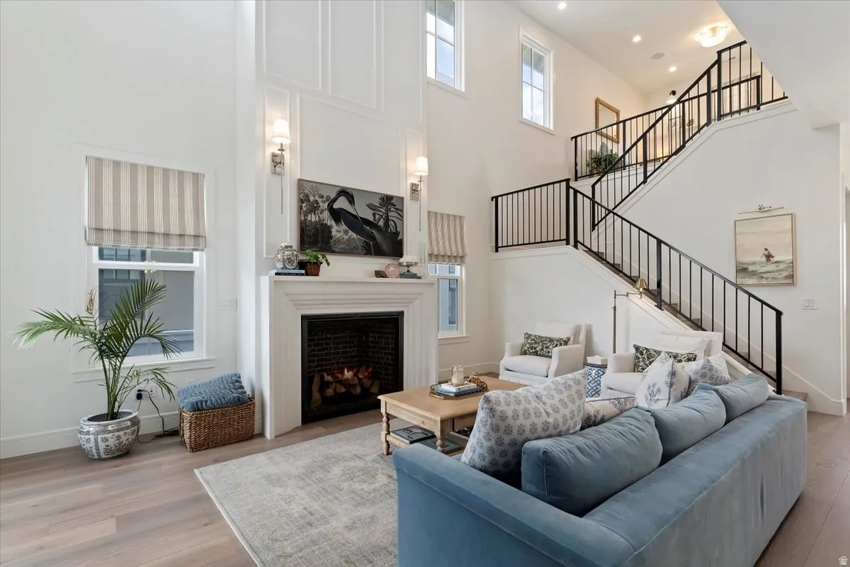 Living room featuring wood finished floors, a lit fireplace, and a high ceiling