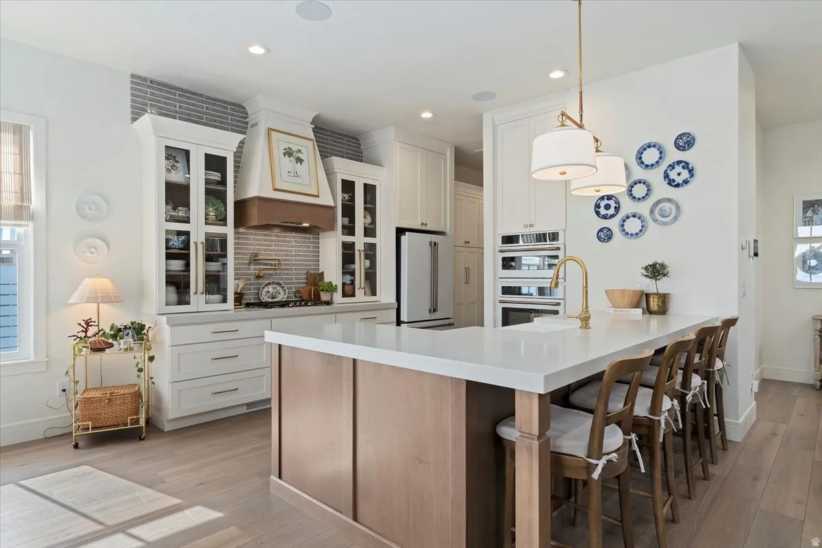 Dual tone kitchen featuring two tone cabinets, glass fronted cabinets, high end refrigerator, a breakfast bar, and a peninsula
