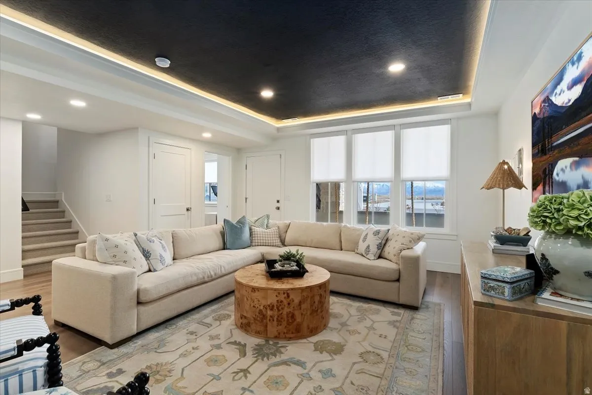 Living room with a tray ceiling, wood finished floors, and recessed lighting