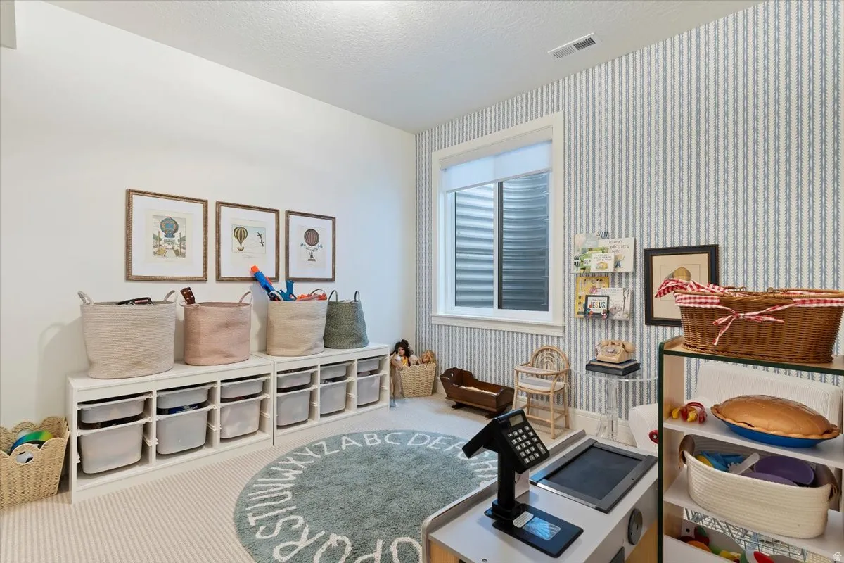 Rec room featuring wallpapered walls, carpet floors, and a textured ceiling