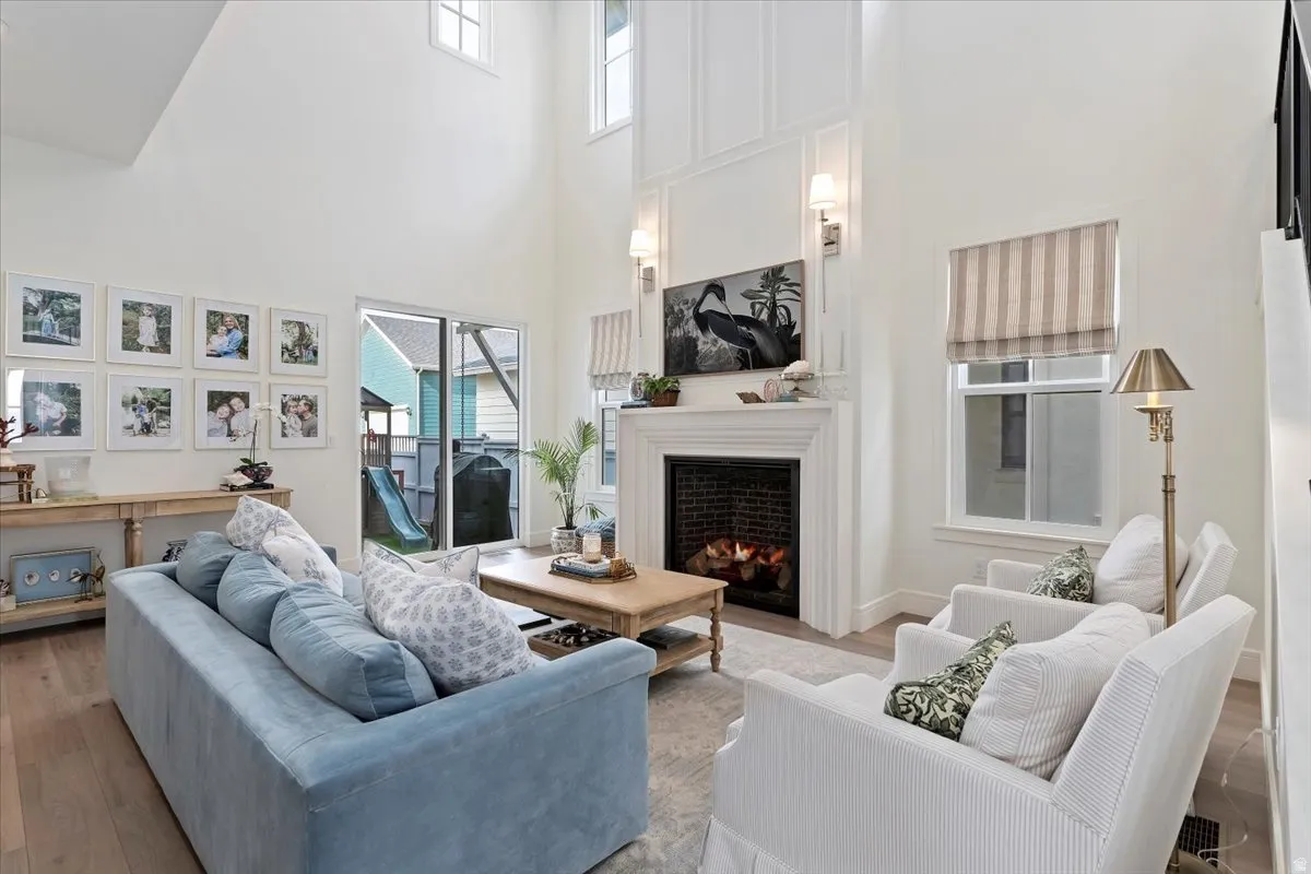 Living area with wood finished floors, a lit fireplace, and a high ceiling