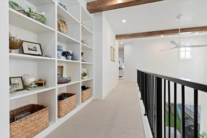 Corridor featuring beam ceiling, recessed lighting, light colored carpet, and built in features