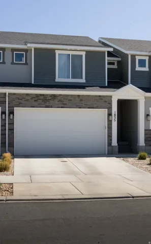 View of front of property featuring concrete driveway, roof with shingles, stone siding, and a garage
