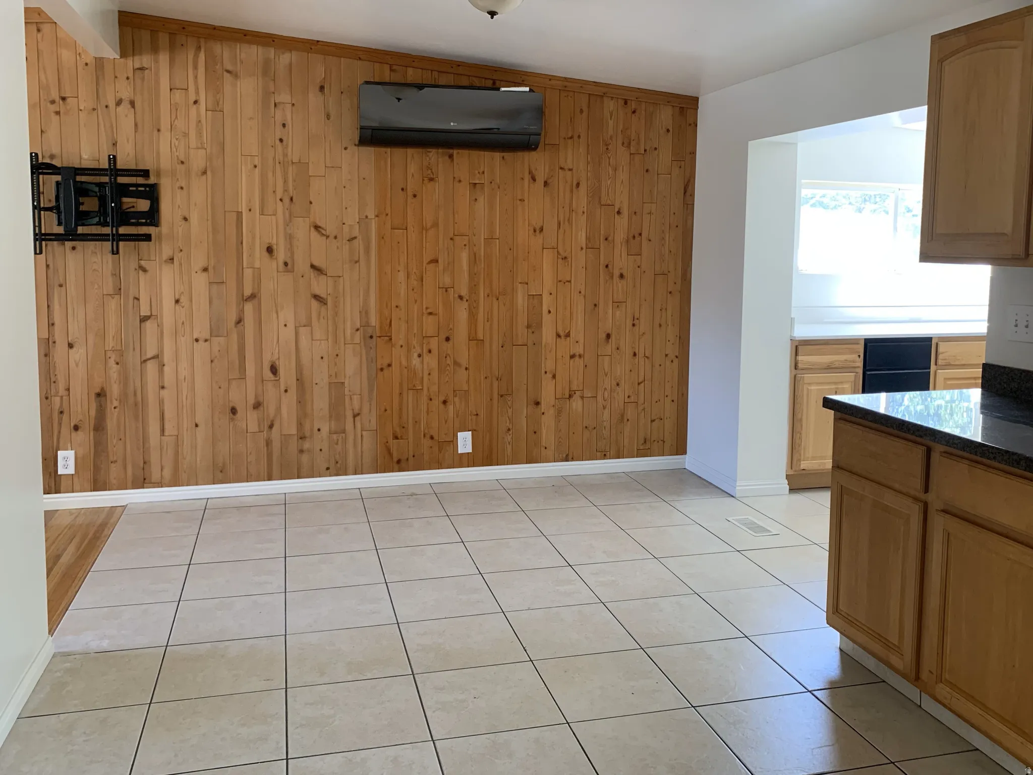 Unfurnished dining area with wooden walls and light tile patterned floors