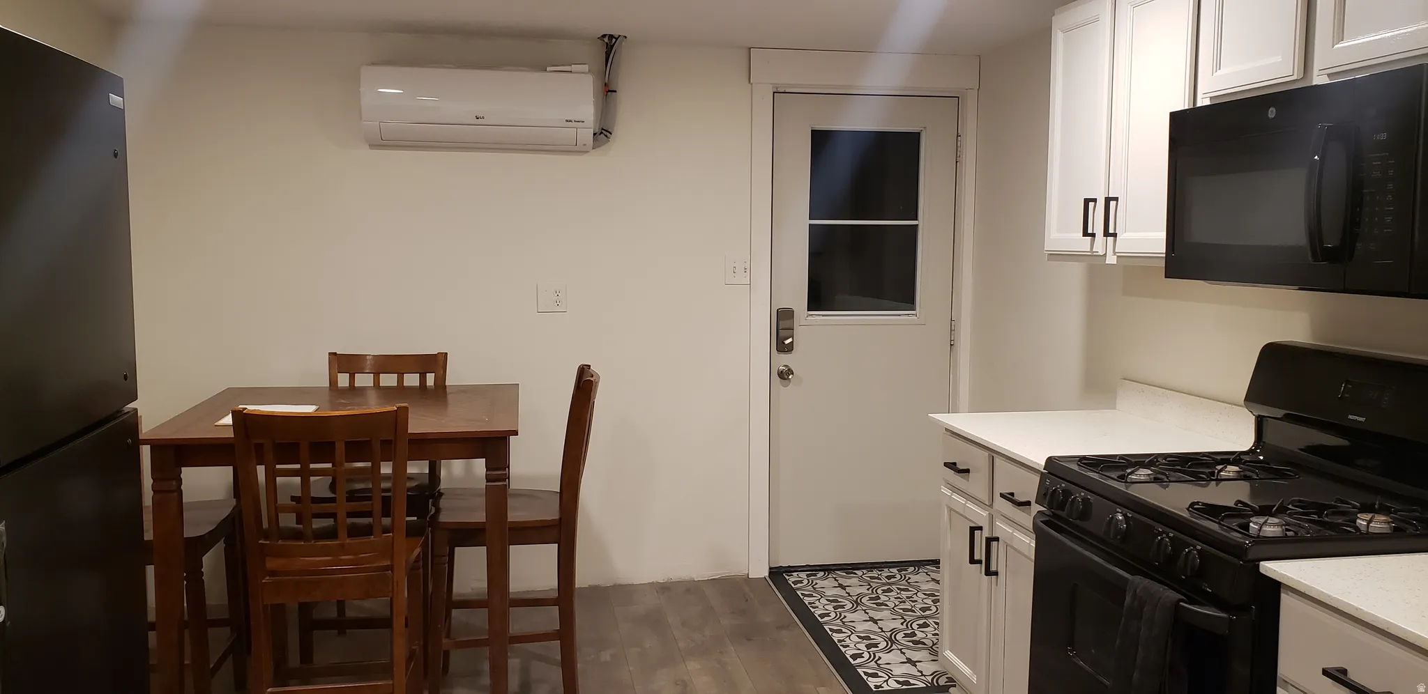 Kitchen featuring black appliances, white cabinetry, dark wood finished floors, and light stone counters