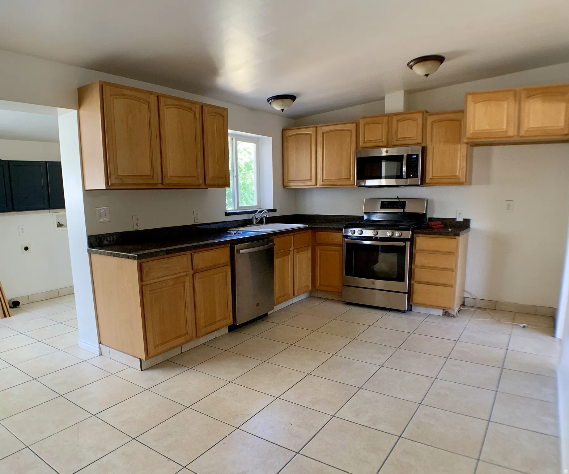 Kitchen featuring stainless steel appliances, light tile patterned flooring, and vaulted ceiling