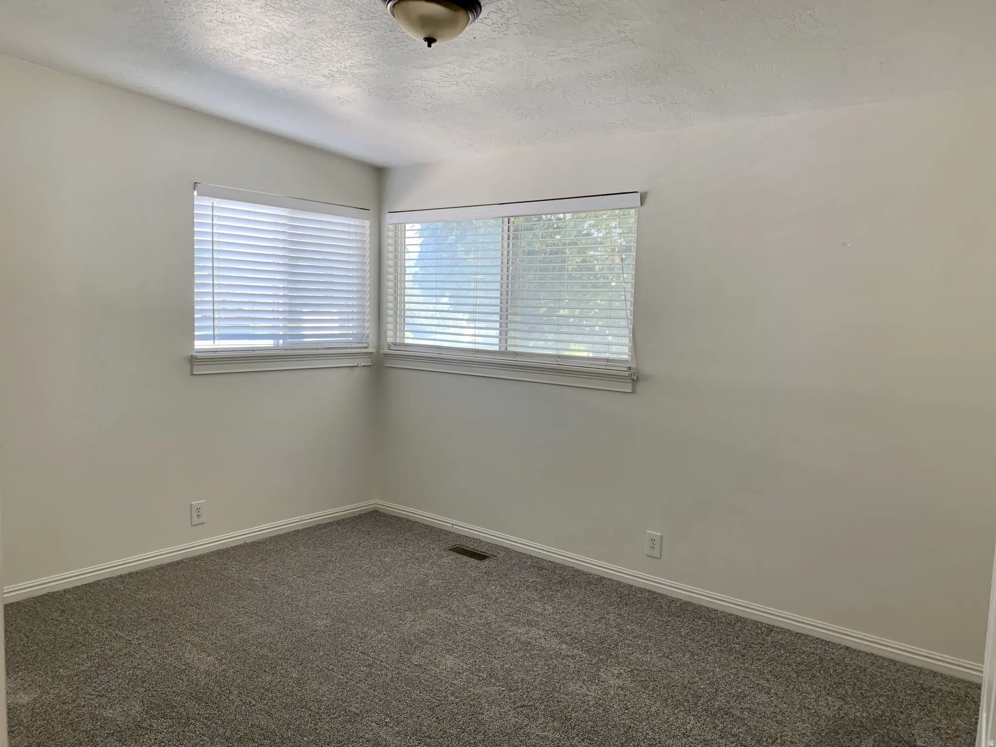 Carpeted empty room featuring a textured ceiling and baseboards