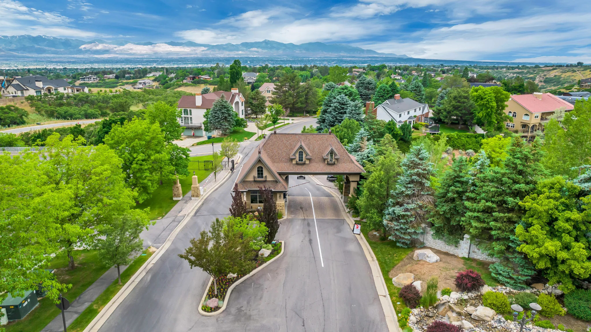 Aerial perspective of suburban area featuring a mountain backdrop and a tree filled landscape