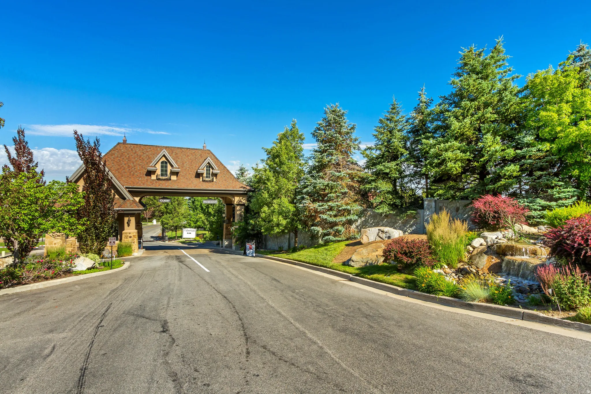 View of asphalt street featuring curbs and a gated entry