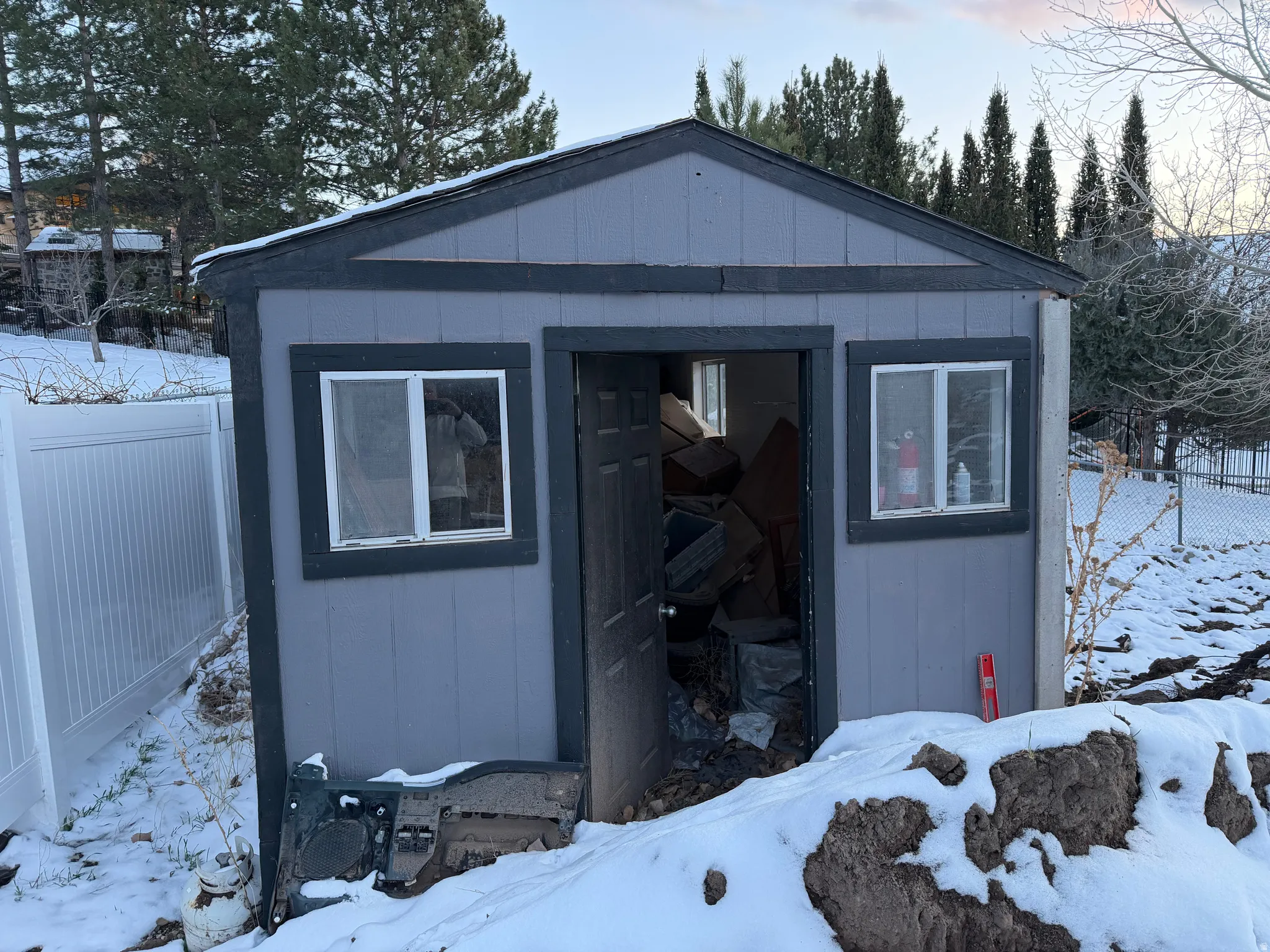 Snow covered structure featuring a fenced backyard and a storage unit