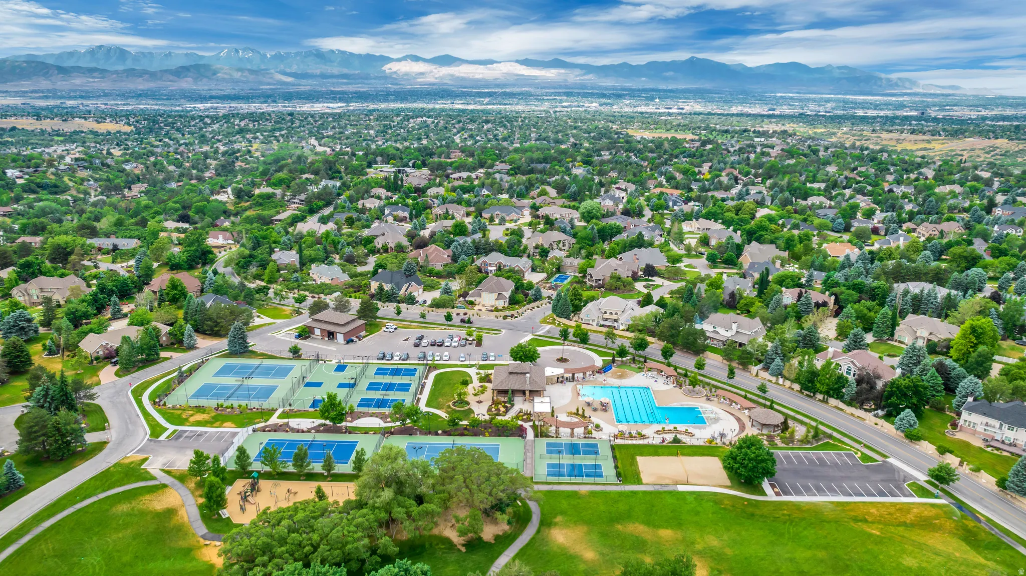 Aerial perspective of suburban area featuring a mountainous background and a pool area
