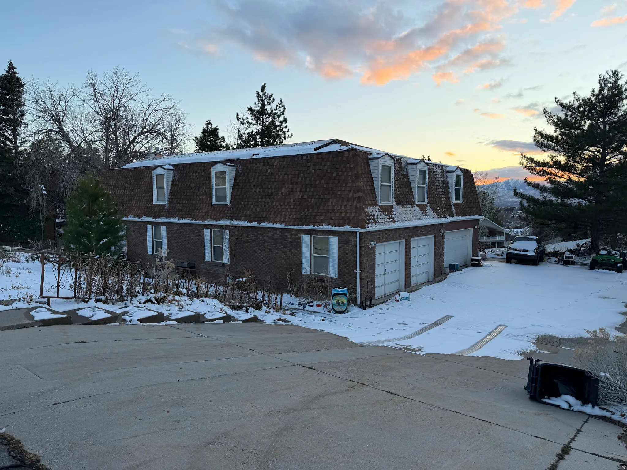 View of front of property featuring brick siding, mansard roof, and a garage