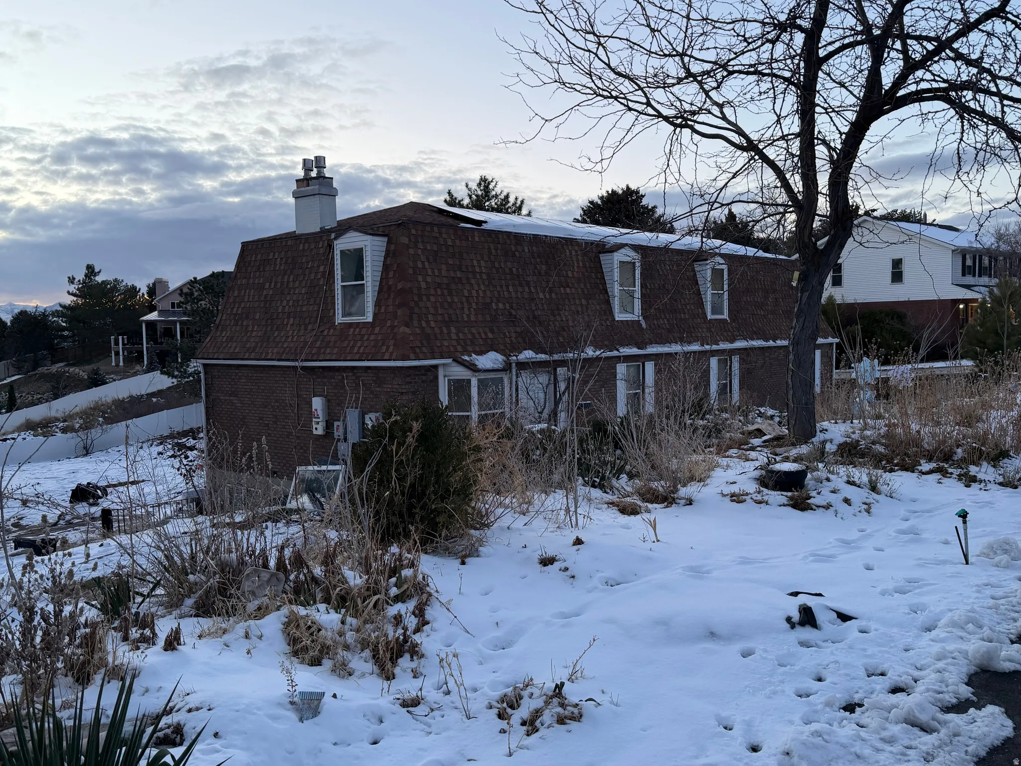 Snow covered house with a chimney and brick siding