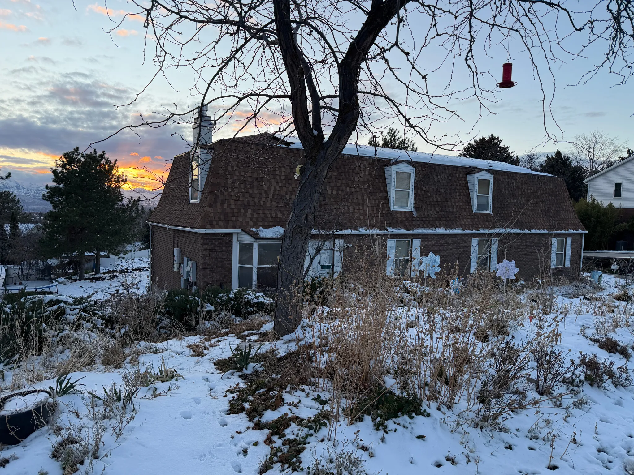 View of front of home with brick siding, a chimney, and a gambrel roof