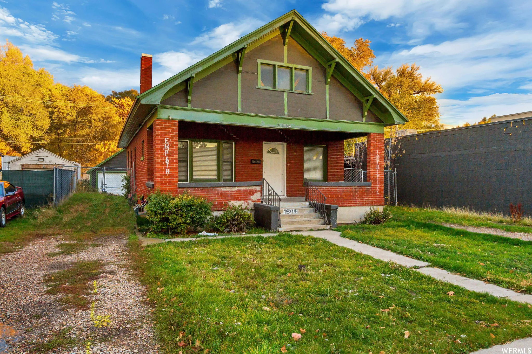 Bungalow-style house with a porch, a chimney, brick siding, and an outdoor structure