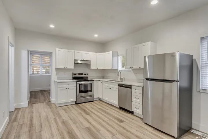 Kitchen with stainless steel appliances, white cabinets, light countertops, light wood finished floors, and recessed lighting