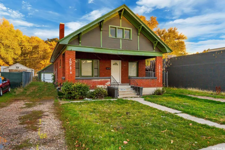 Bungalow-style house with a porch, a chimney, brick siding, and an outdoor structure
