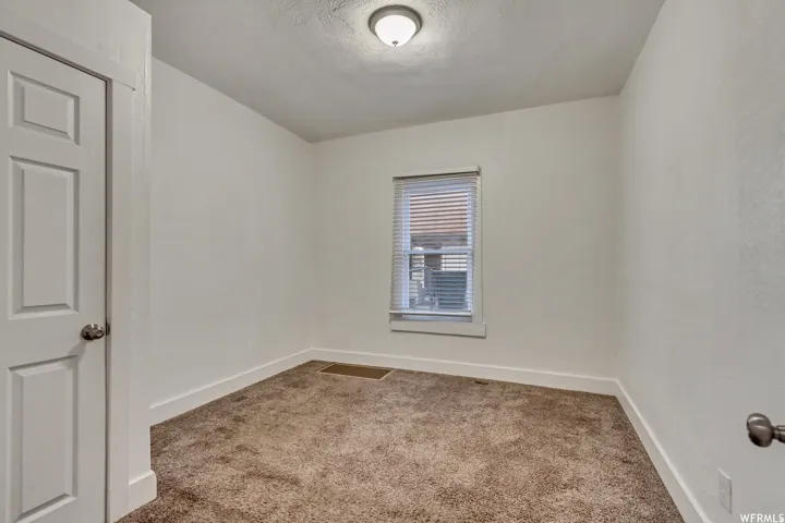Unfurnished room featuring light colored carpet and a textured ceiling