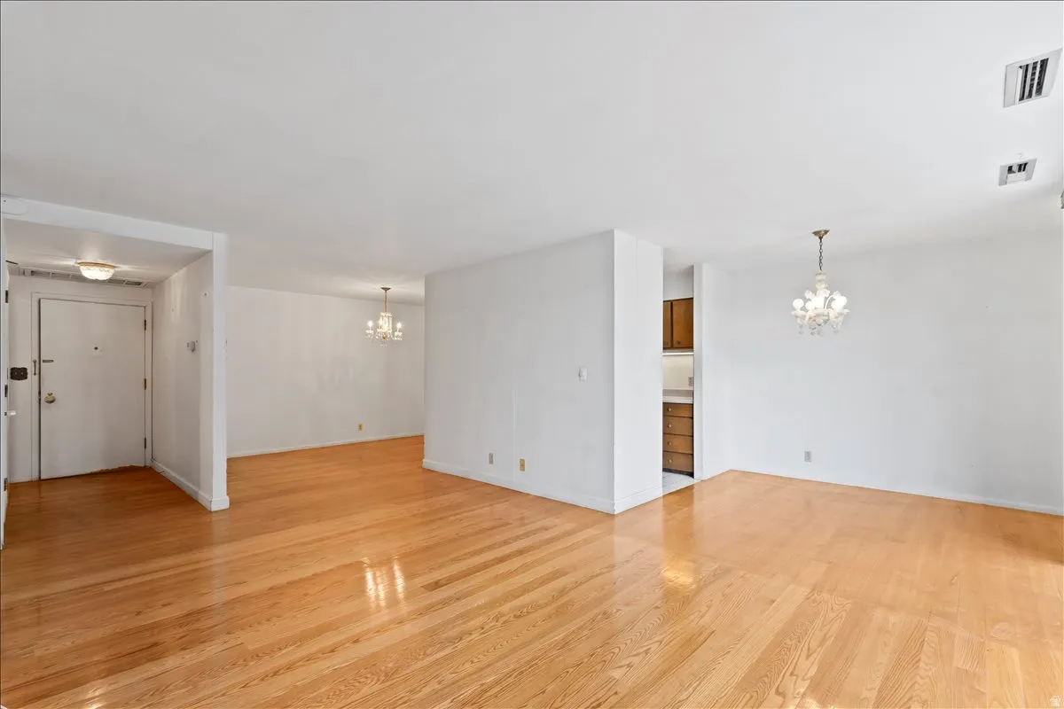 Unfurnished living room with hanging lights and light wood-style flooring