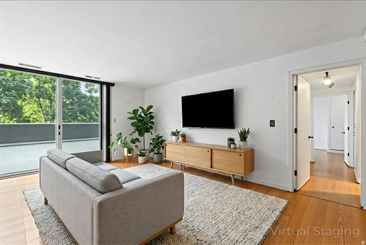 Living area featuring wood-finish flooring, white walls, and a sliding glass door leading to an outdoor balcony