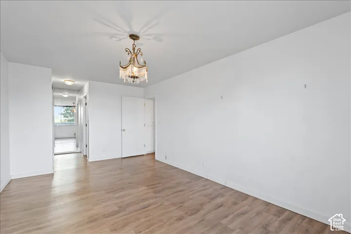 Unfurnished bedroom with hanging lights and light wood-style flooring