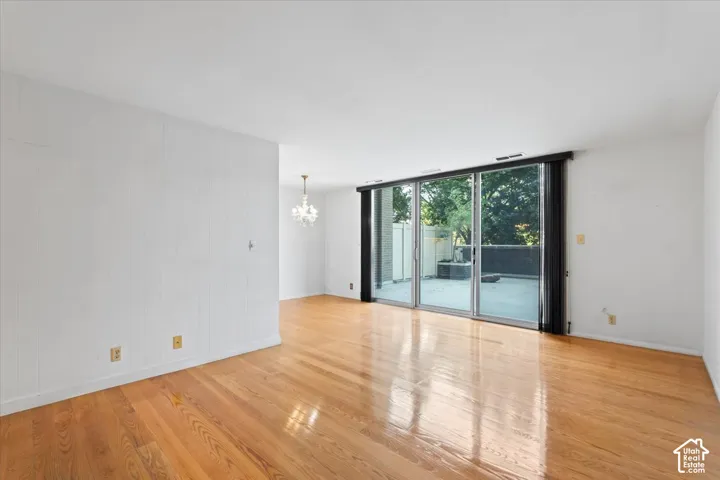 Expansive room featuring wood-finish flooring, white walls, and a full wall of sliding glass doors