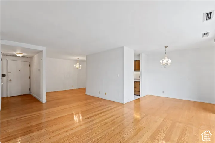 Unfurnished living room with hanging lights and light wood-style flooring