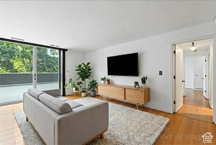 Living area featuring wood-finish flooring, white walls, and a sliding glass door leading to an outdoor balcony