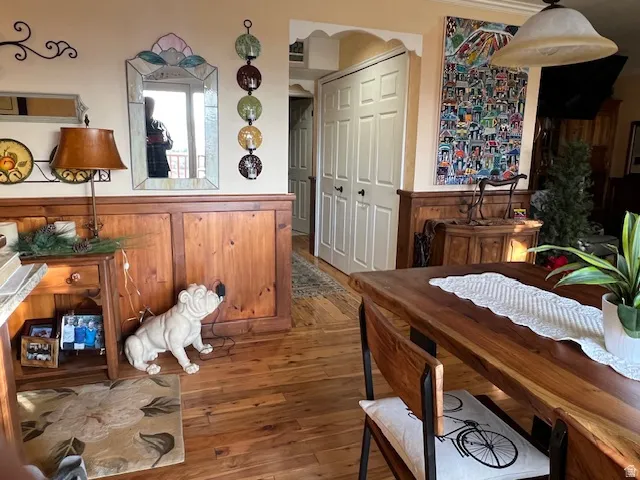 Dining area featuring hardwood / wood-style floors, arched walkways, and a wainscoted wall