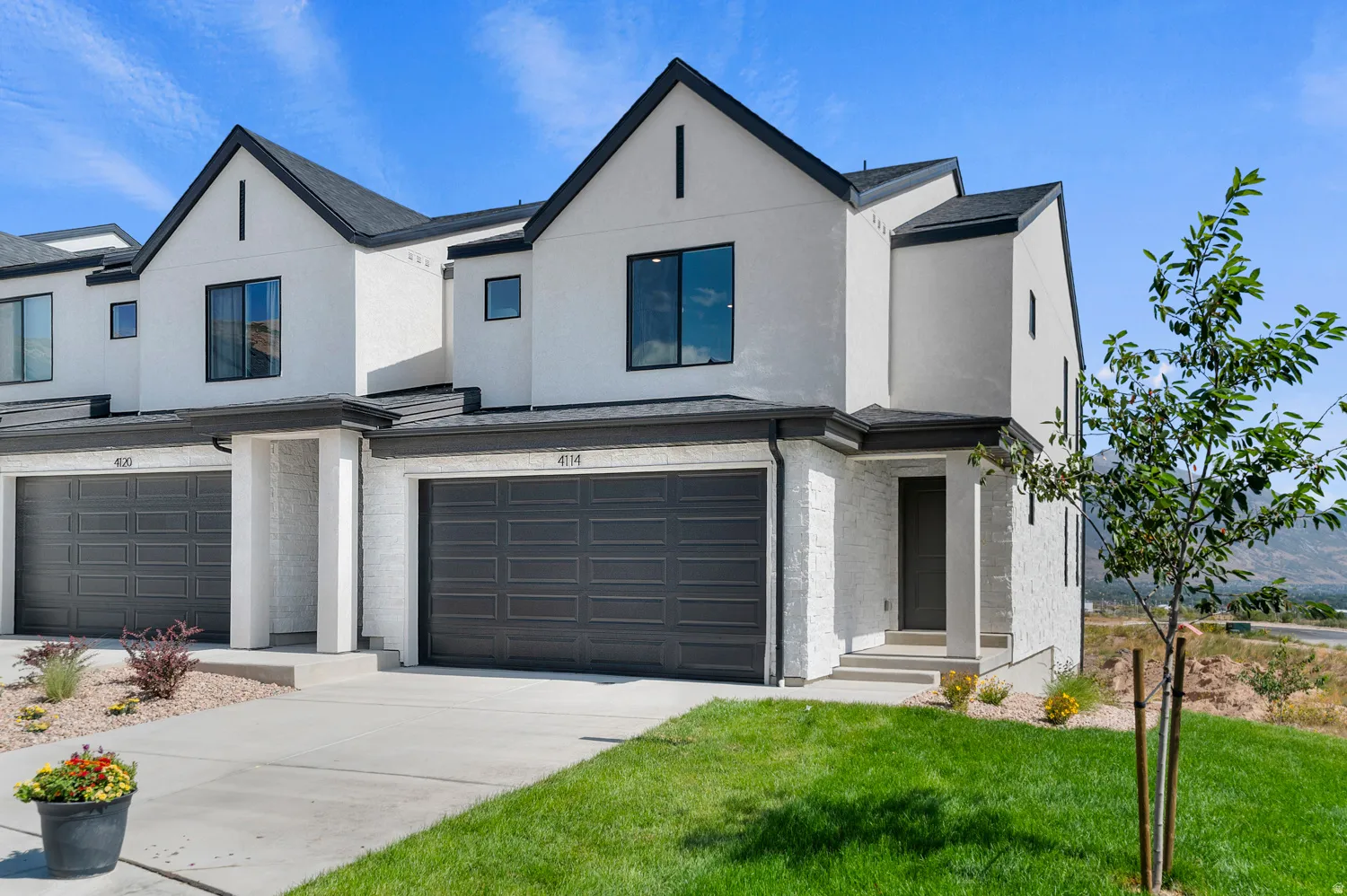 View of front of property with an attached garage, stucco siding, driveway, and a front yard