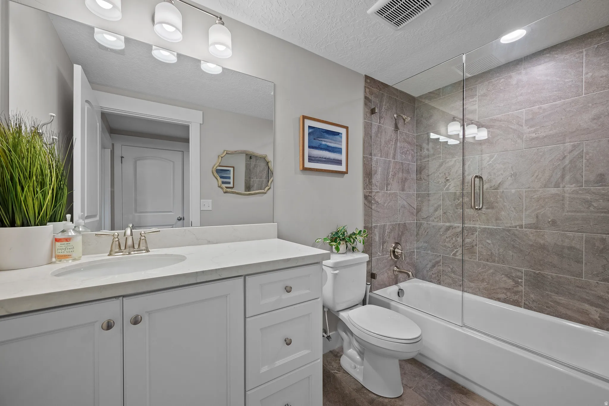 Full hall bathroom with tiled tub surround, tub and shower.   Full glass door.