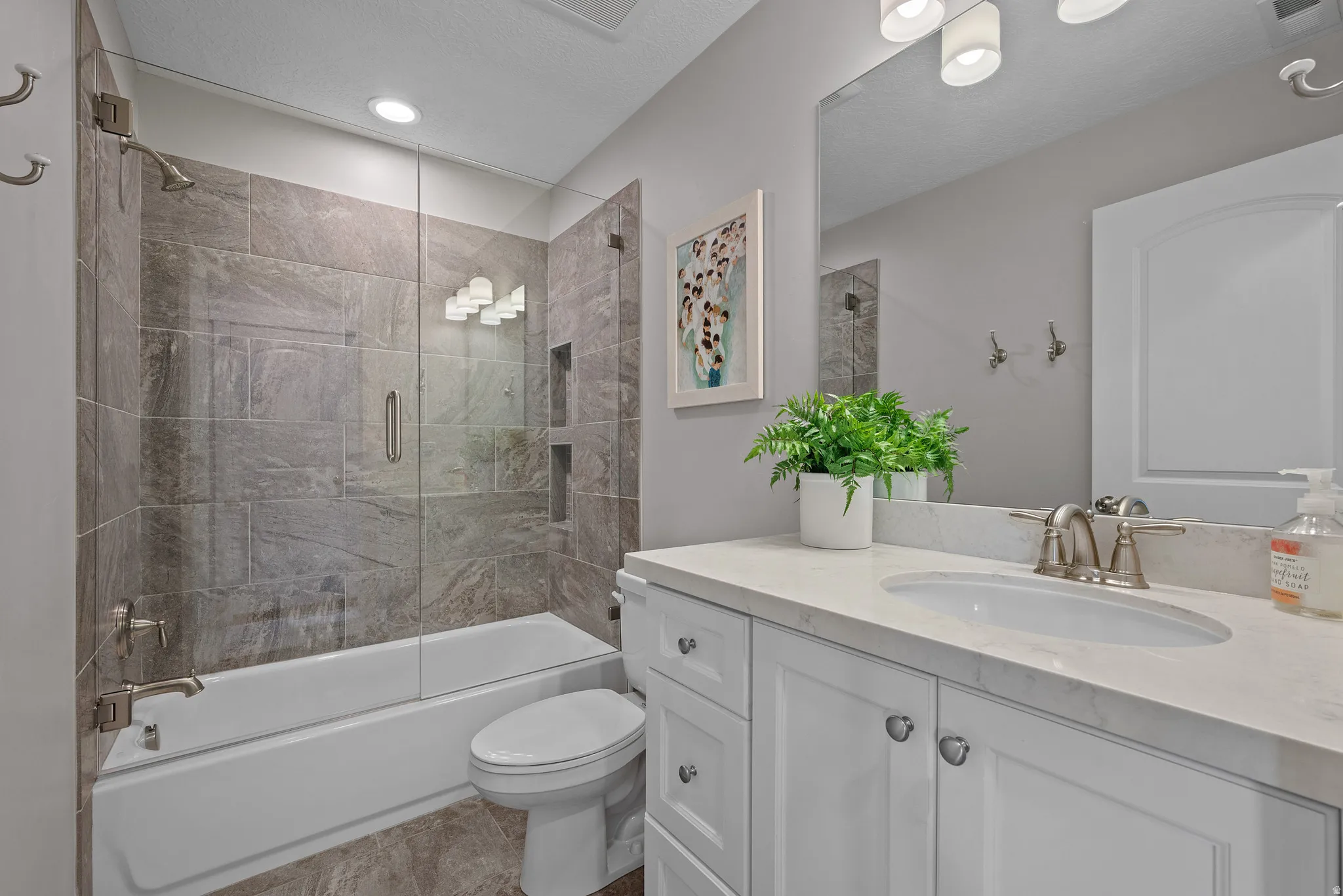 Full hall bathroom with tiled tub surround, tub and shower. Full glass door.