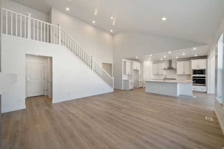 Unfurnished living room featuring recessed lighting, light wood-type flooring, and a high ceiling