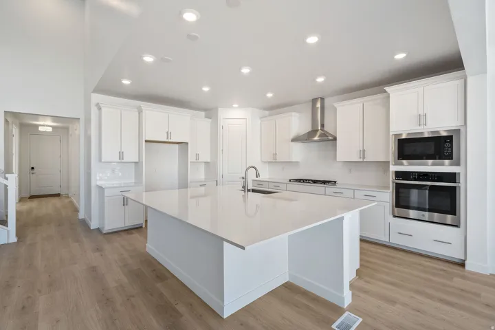 Kitchen with white cabinets, stainless steel appliances, tasteful backsplash, recessed lighting, and light wood finished floors