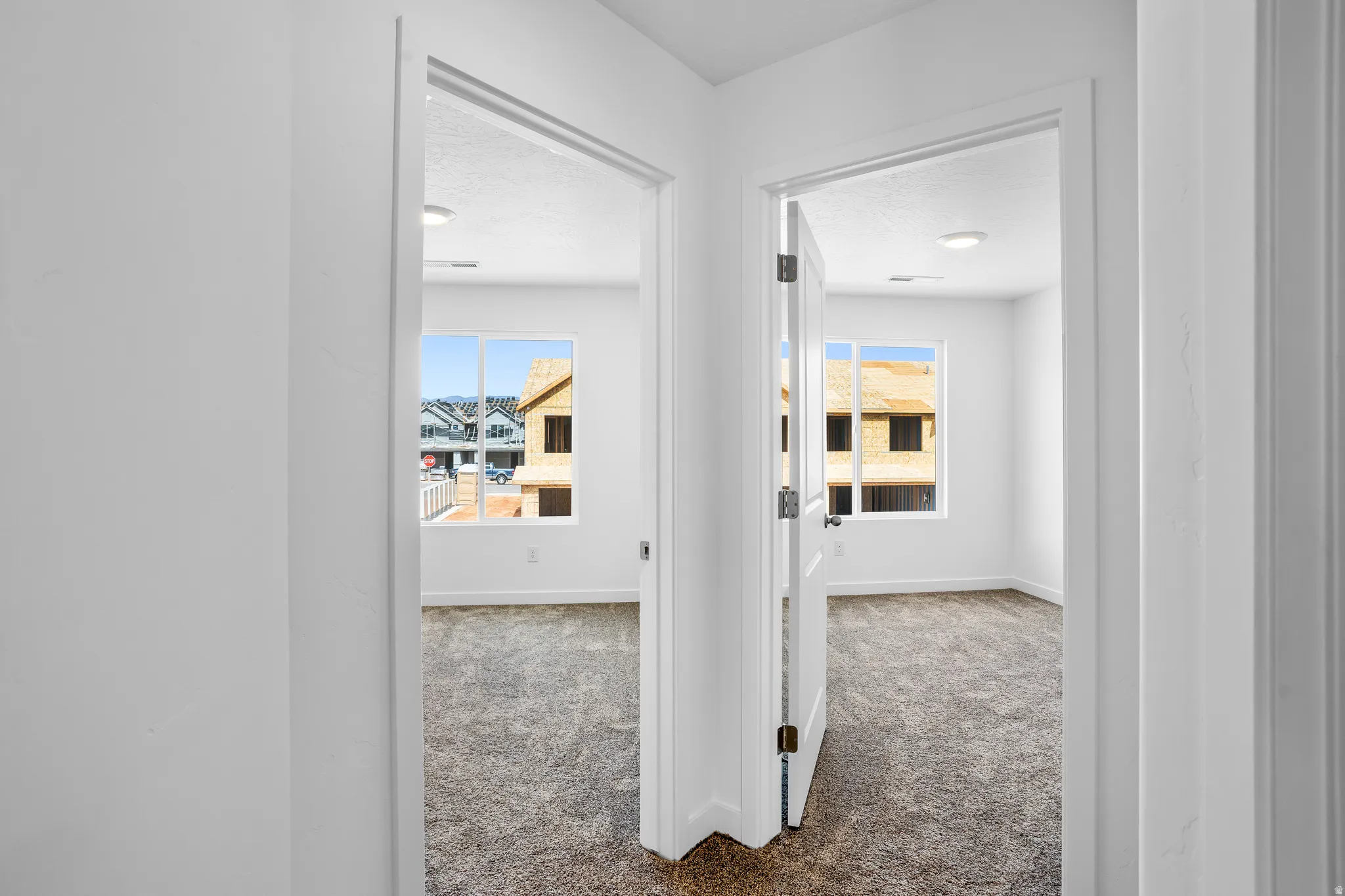 Hallway featuring light colored carpet and baseboards